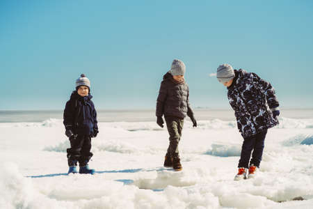 children walking on icey beach of finland gulf on spring sunny day. image with selective focus.の写真素材