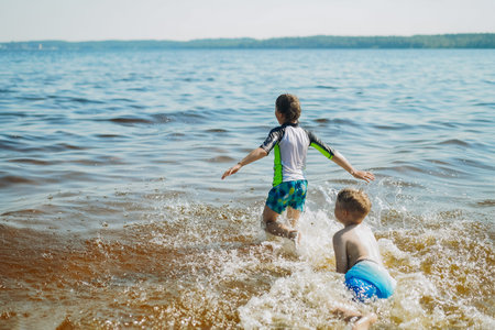 cute caucasian boys running into water with splashes and laughter. Vacatiom on the sea side. happy childhood. Image with selective focus.の写真素材