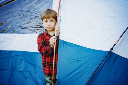 cute little caucasian boy looking out from touristic tent. Family camping concept. high quality...
