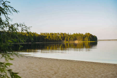 beautiful sunset at Ladoga lake. Sand beach and blue sky. Pine forest background. Beauty of russian, Karelian nature. Image with selective focusの写真素材