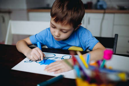 Adorable little toddler boy intensely drawing with color crayons. Image with selective focus. high quality photoの写真素材