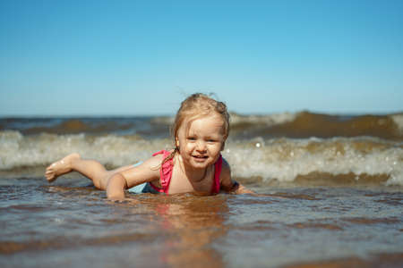 Little girl lying on the sand on the beach. Image with selective focusの写真素材