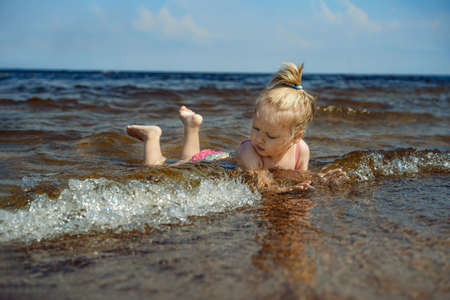 Little girl lying in sea in waves. image with selective focusの写真素材