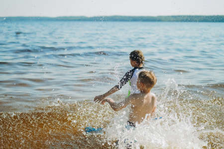 cute caucasian boys running into water with splashes and laughter. Vacatiom on the sea side. happy childhood. Image with selective focus.の写真素材
