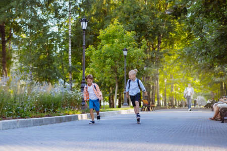 children go to school with backpacks on sunny day. Beginning of academic year. Image with selective focusの写真素材