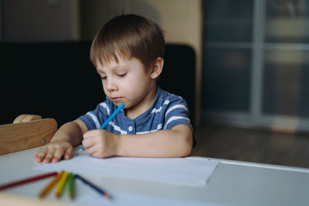 Adorable little toddler boy passionately drawing with color pencils. Image with selective focus . high quality photoの写真素材