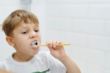 cute 5 years old boy brushing teeth with bamboo tooth brush in bathroom. Image with selective focus....