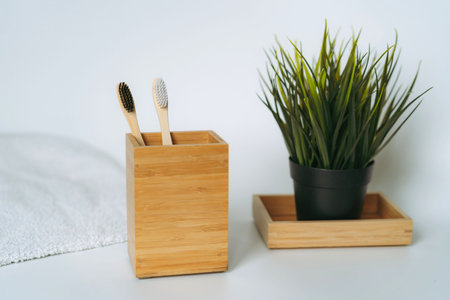 two toothbrushes in bamboo folder. white towel and artificial flower on white background. Eco friendly conceptの写真素材