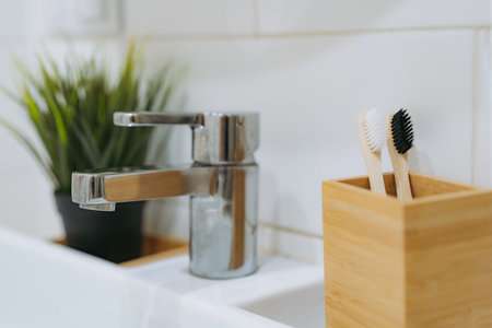two toothbrushes in bamboo holder and a flower on white surface of bathroom sink. Eco friendly conceptの写真素材