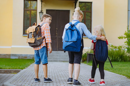 children running to school with backpacks on sunny day. Brother accpmpany little sister. Beginning of academic year. Boys and girls by school doorstep. Image with selective focusの写真素材