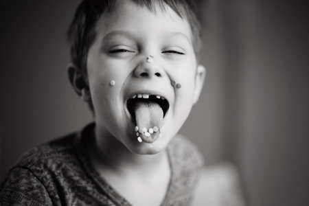 cute little boy putting his tongue out covered with sugar topping. Image with selective focus and toning. High quality photoの写真素材
