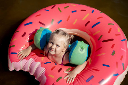 cute little caucasian girl swimming in lake on rubber ring. Summer vacation concept.の写真素材