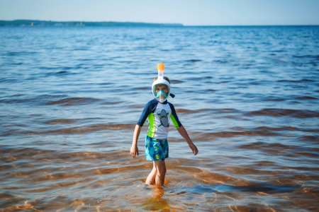 cute little caucasian boy wearing snorkeling mask going out from the seaの写真素材