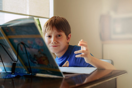 caucasian boy doing homework at home at the desk by the window. Image with selective focus