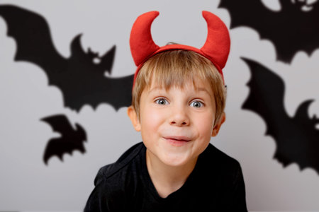 Halloween concept. cute little boy with red devil horns. Bats images on white background