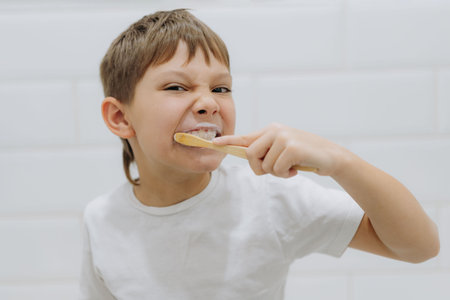 cute 8 years old boy brushing teeth with bamboo tooth brush in bathroom. Image with selective focus. High quality photoの写真素材