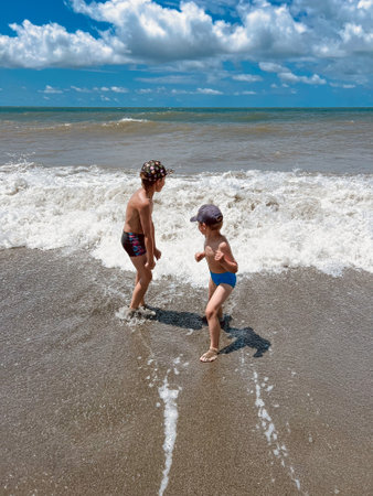 caucasian boys catching waves in the sea during storm. Children enjoys swimming in the ocean.Holidays, vacation with kids. Image with selective focusの写真素材