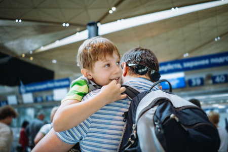 Father holding cute caucasian boy in airport with backpack. Traveling with kidsの写真素材