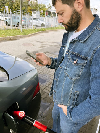 Man making contactless payment using smartphone for refueling car at gas station.の写真素材