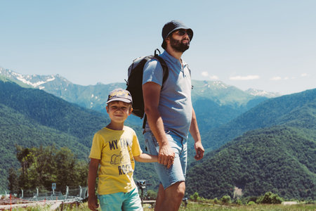 millenial bearded tourist man hiking in mountains with child. father and son spend time togetherの写真素材