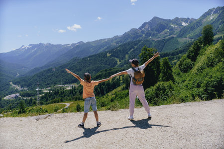 young stylish woman holding childhand enjoying beauty of mountains. family hiking conceptの写真素材