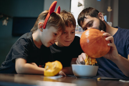 Children with father carving a traditional Jack lantern from pumpkin. Halloween concept. Image with selective focusの写真素材