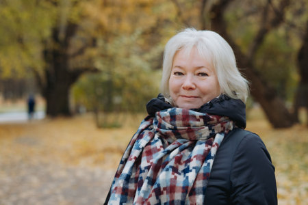 portrait of happy smiling senior womanin autumn parkの写真素材