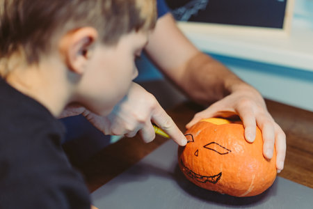 Children with father carving a traditional Jack lantern from pumpkin. Halloween concept. Image with selective focusの写真素材