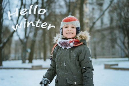 cute caucasian 7 years old boy in knit hat and khaki parka with Hello winter textの写真素材