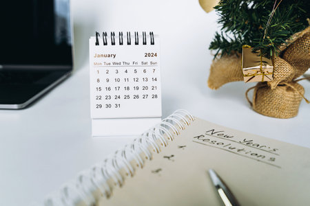 open notepad with resolutions for new 2024 year text. Near laptop, calendar and christmas treeの写真素材
