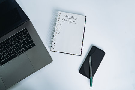 open notepad with resolutions for new 2024 year text. Near laptop, and smartphoneの写真素材