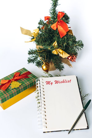 open notepad with christmas wish list text. decorated christmas tree and gift box on background. Vertical imageの写真素材