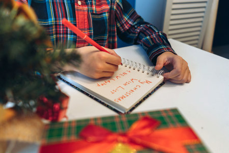 unrecognizable boy writing christmas wish list sitting at the table at homeの写真素材