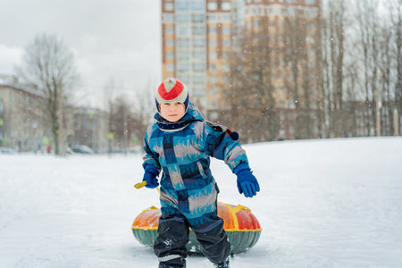 cute caucasian with snow tubing in park . Winter activities concept. happy childhood. Image with selective focus.の写真素材