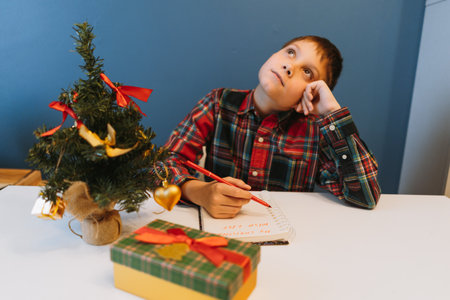 unrecognizable boy writing christmas wish list sitting at the table at homeの写真素材