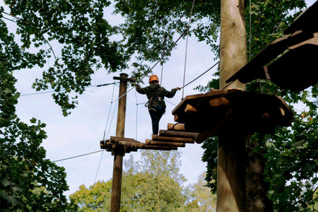 well equipped teenage boy in outdoor passing obstacle course. Active recreation in high rope parkの写真素材