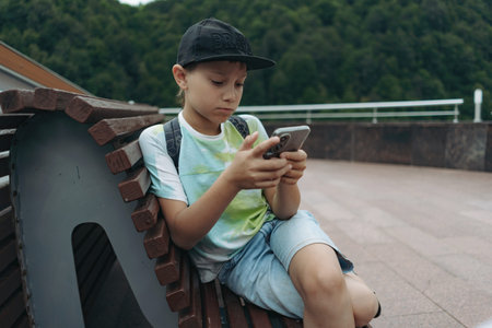 Caucasian boy using smartphone texting message. Traveling in mountains
