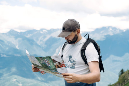 tourist man hiking in mountains looking at the map for direction. High quality photo