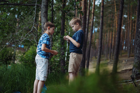boys fishing by the lake in forest trying to untwine knot of fish wireの写真素材