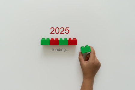 Loading new year 2024 to 2025 with child hand putting green plastic block in progress bar. Start new year 2025 with goal plan, goal concept, strategy.の写真素材