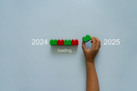 Loading new year 2024 to 2025 with child hand putting plastic block in progress bar.