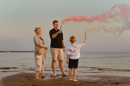 Gender reveal announcement with pink smoke on beach. Family expecting baby girl. High quality photoの写真素材