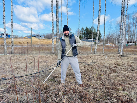 a man raking dry grass in spring at his country plotの写真素材