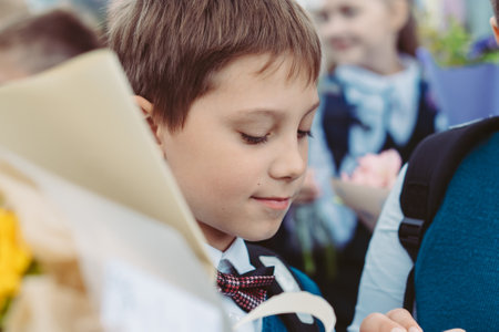 A 10-year-old boy carries a bouquet of flowers before school on September 1st, dressed in formal attire with a backpack.の写真素材