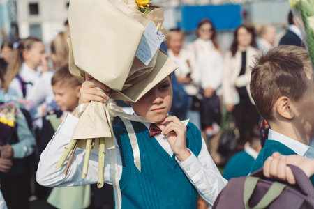 A 10-year-old boy carries a bouquet of flowers before school on September 1st, dressed in formal...