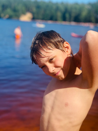 cute teen age boy by the forest lake at sunny summer day. High quality photoの写真素材