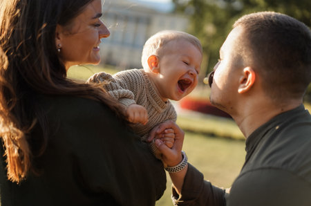happy young caucasian family with baby boy having fun in a park.