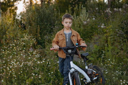 cute caucasian boy cycling on the glade of fireweed in countrysideの写真素材