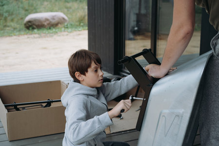 teenage boy assemble a wheelbarrow with a screwdriver, father assistsの写真素材