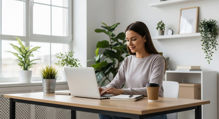 Smiling businesswoman working on laptop at workplace in office, copy spaceの素材
